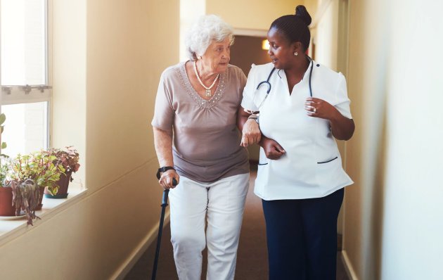 caregiver assisting senior woman walking using her walking stick